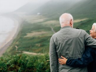 A couple standing on the mountain in front of the sea.
