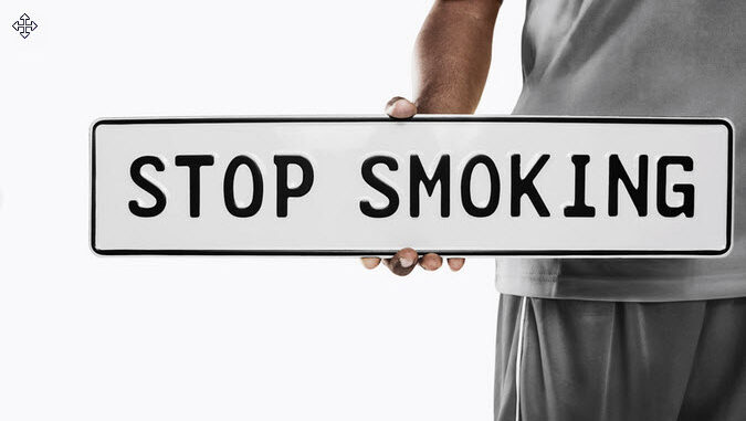 A person holding a Stop smoking sign.