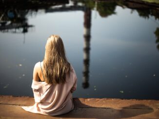 A woman sitting next to a lake