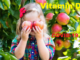 A young girl standing in front of the apple tree with two apples cover her eyes with phase vitamin D and covid 19