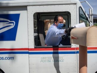 The shipping man putting a letter to mail box.
