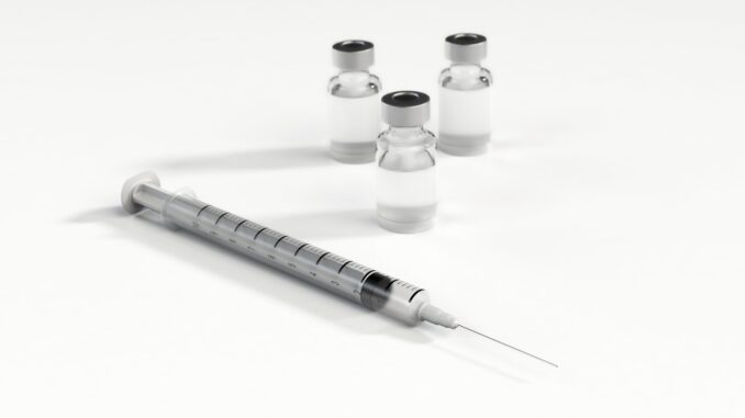 A syringe and three bottles of medicine.