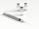 A syringe and three bottles of medicine.